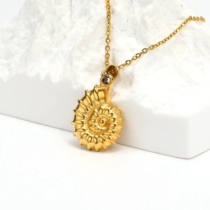 Macro-opname van 18k gouden schelphanger aan ketting op witte gestructureerde steen