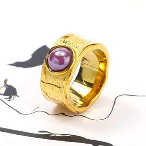 Macro view of gold irregular textured ring featuring a large round purple ceramic stone