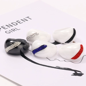 Glossy black and white acrylic rings set with curved rows of colorful rhinestones