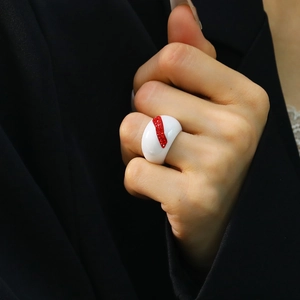 Minimalist white ceramic ring with diagonal red rhinestones on black suit background