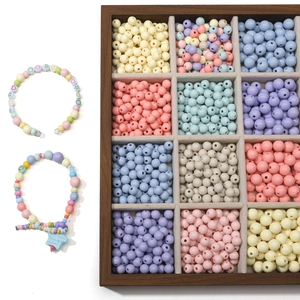 Detail view of 8-10mm cream acrylic round beads in a 12-grid wooden tray for DIY crafts