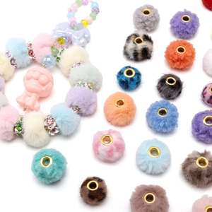 Dettaglio di perline pompon colorate in peluche con grandi fori dorati per gioielli fai da te