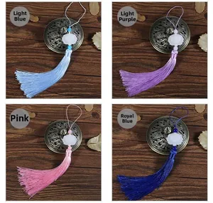 Detail of four colorful Chinese style tassels with faux jade petals on a dark wood background