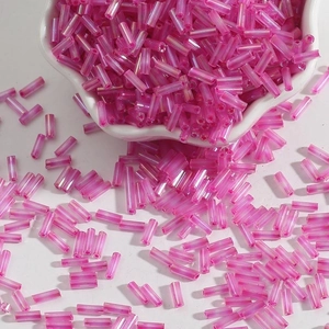 Translucent pink glass bugle beads in a ceramic bowl for DIY jewelry making
