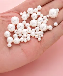 Detailansicht weißer Glasperlen in verschiedenen Größen in der Hand zum Größenvergleich