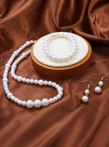 Detalle de un conjunto de joyas con perlas de vidrio blancas sobre elegante fondo de seda