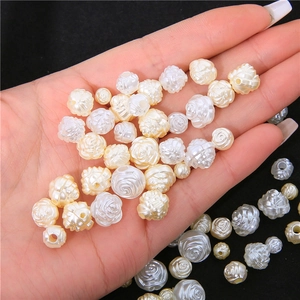 Hand holding vintage acrylic rose pearl beads for DIY jewelry making in cream white