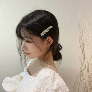 Elegant side hair clip with comb shape and pearls decoration on female model side profile