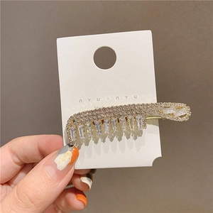 Close-up of gold tone hair clip with sparkling rhinestones and crystal stones on card