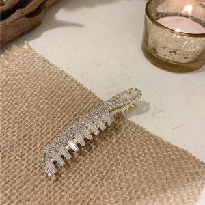 Detail view of sparkling rhinestone and rectangle crystal hair clip on a golden base