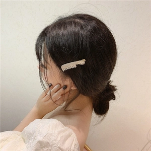 Detailed close-up of a gold comb hair clip with sparkling rhinestones on dark hair