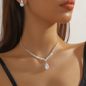 Detail of elegant silver teardrop pendant necklace and crystal earrings worn by model