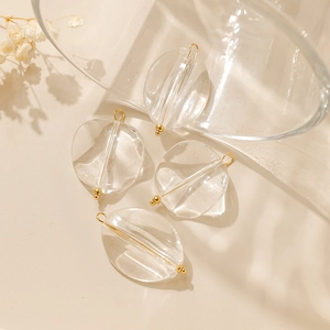 Close-up of four transparent oval geometric pendants with gold metal needles for DIY jewelry