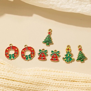 Lot de breloques de Noël en émail avec cloche, sapin et couronne sur fond tricoté