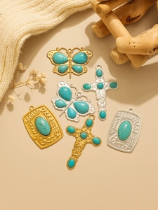 Flat lay of vintage turquoise bohemian cross and butterfly stainless steel pendants