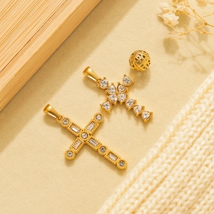 Golden cross pendants with white zircon inlays and hollow gold beads on warm background