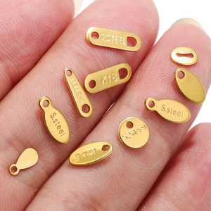 Gold stainless steel jewelry tags with S.STEEL and S925 engraving held in hand