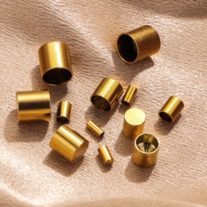 Gold stainless steel cylinder connectors for DIY jewelry making on silk background