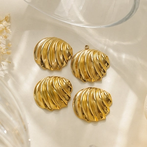 Détail de quatre pendentifs coquillages dorés avec texture rayée fine sur tissu beige
