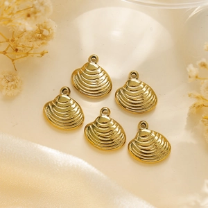 Vue détaillée de 5 pendentifs coquillages dorés texturés sur un tissu en satin