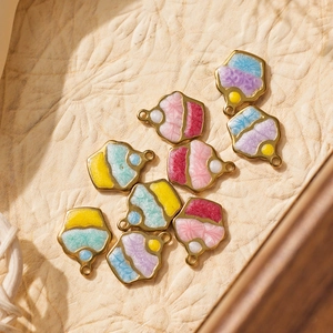 Vue macro de breloques gâteau en émail coloré avec paillettes et boucles dorées