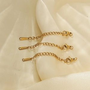 Détail de trois chaînes d'extension en acier plaqué or 18k avec fermoirs mousqueton