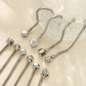 304 stainless steel snake chain bracelets with heart, flower, and crown charms on beige display