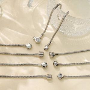 Detail of silver snake chain bracelets with crown, heart, and clover clasp designs