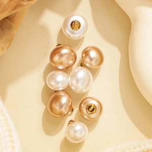 Detalle de botones redondos efecto perla en tonos blanco crema y dorado champán