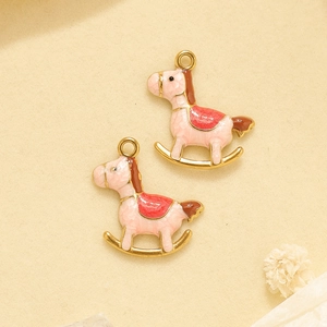 Détail de pendentifs chevaux à bascule en émail rose et plaqué or pour création DIY