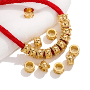 Macro shot of gold cylinder spacer beads with detailed knurled edges on a red cord
