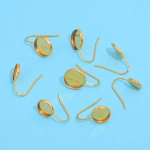 Macro view of gold-plated stainless steel U-shaped earring hooks with round bezel settings