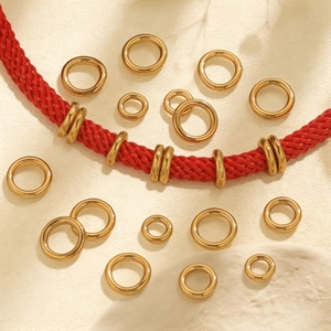 Detailed view of various sizes of gold stainless steel jump rings on a red cord
