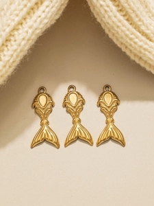 Detailed view of three golden mermaid tail pendants with embossed patterns on knit fabric