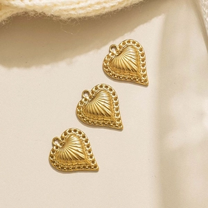 Detalle de tres colgantes de corazón dorados con texturas radiales y bordes de cuentas