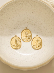 Detalle macro de tres colgantes florales ovalados bañados en oro 18K sobre cerámica