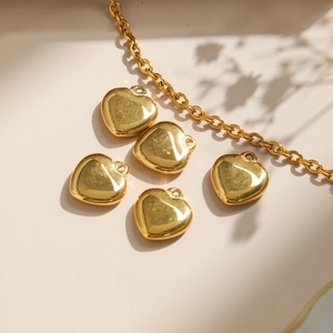 Colgantes de corazón en acero inoxidable 304 dorado y cadena fina sobre fondo beige