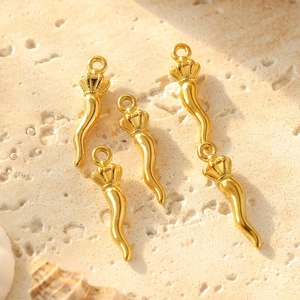 Golden cornicello horn pendants with crown detail on a textured stone background