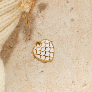 Macro shot of gold heart pendant with white enamel scales and vintage texture