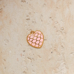 Detailed macro view of heart-shaped pendant with pink enamel and gold scales pattern