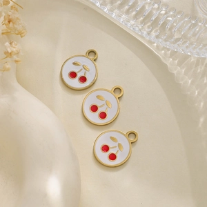Close-up of white enamel cherry charms with gold stainless steel edges for DIY jewelry