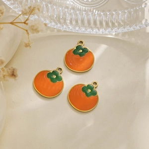 Macro detail of three orange persimmon enamel pendants with gold trim for DIY jewelry