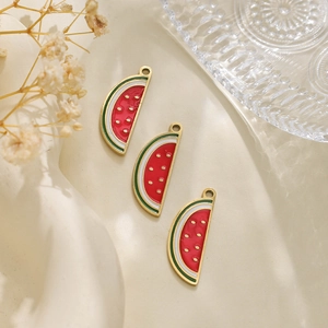 Macro detail of three watermelon slice charms with red enamel and gold seed accents