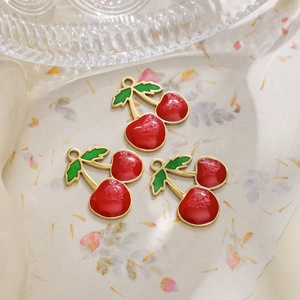 Detailed view of three cherry pendants with bright red enamel and gold-plated edges