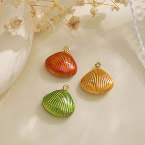Detailed macro view of three colorful shell charms in orange, yellow and green enamel