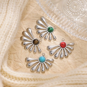 Detailed view of fan-shaped steel pendants with colorful stone inlays on knit fabric