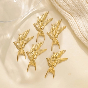 Detailed macro view of gold-plated stainless steel swallow pendants with feather textures
