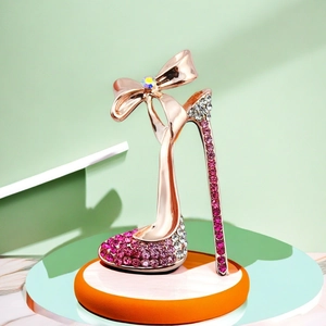 Funkelnde Brosche in High-Heel-Form aus Roségold mit Kristallschleife auf Podest