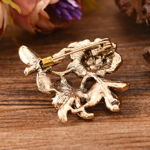 Vintage gold peony flower brooch with enamel and pearls, back view on wood background