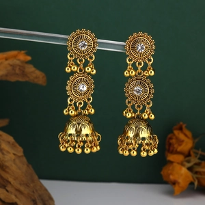 Dettaglio di orecchini Jhumka indiani dorati con borchie a sole e nappe a campana